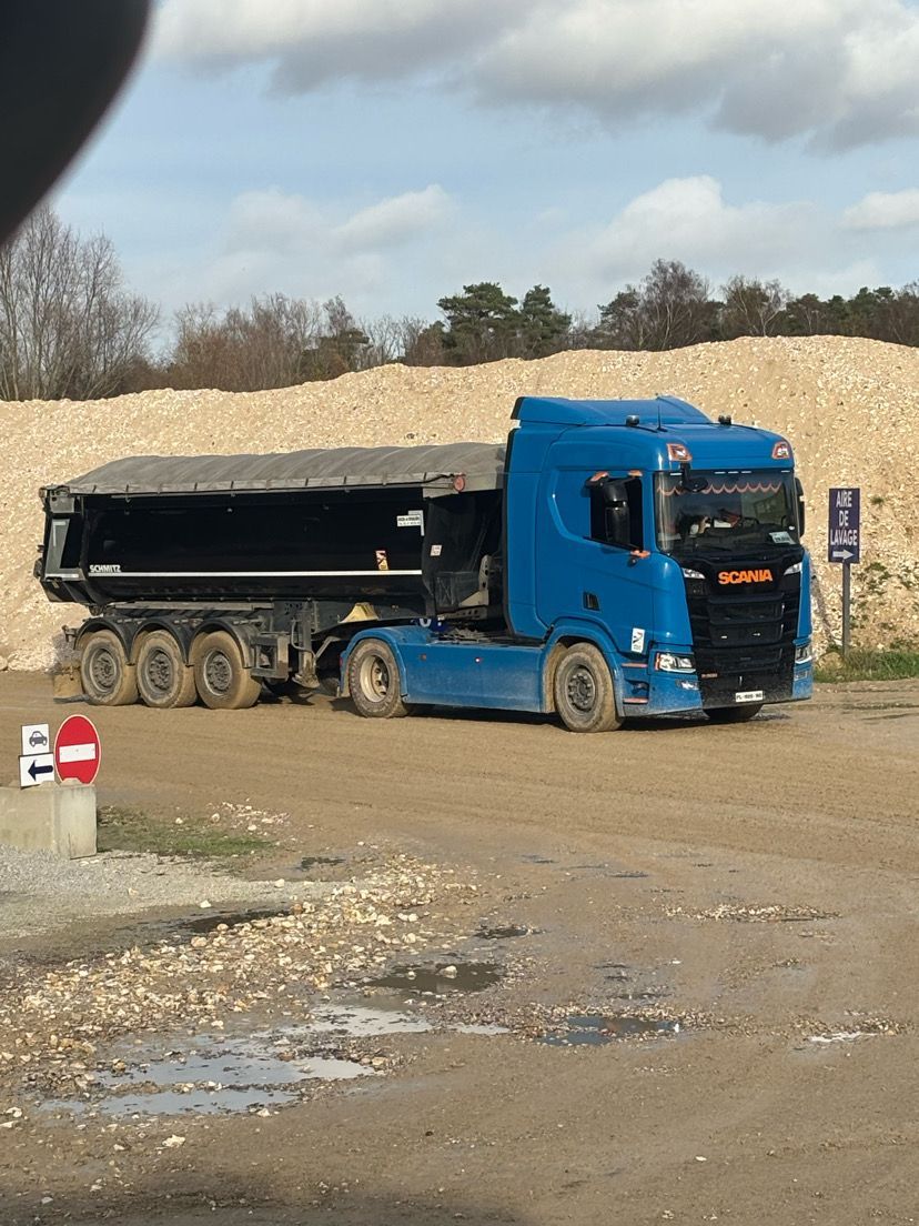 Camion-poubelle noir et jaune stationné dans la rue, devant un immeuble.