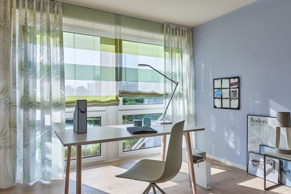 Büro mit vorgezogenen Gardinen und heller Einrichtung