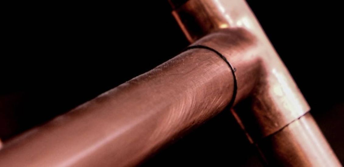 Un primer plano de un tubo de cobre sobre un fondo negro.