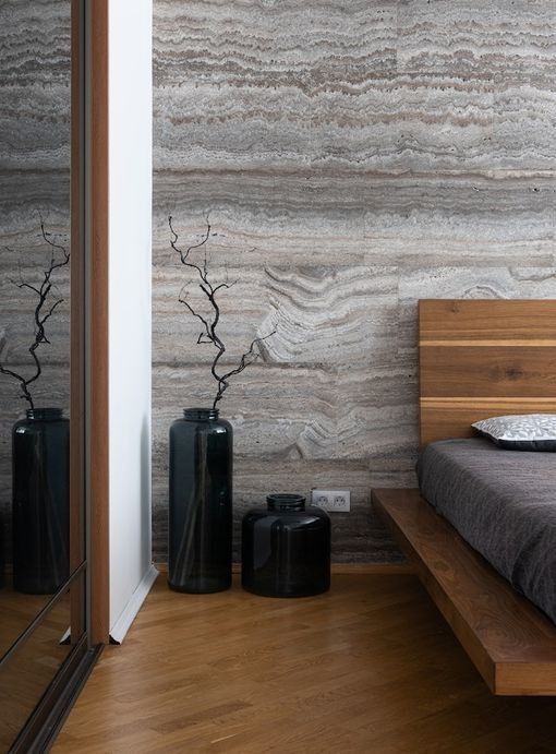 Un dormitorio con una cama de madera y una pared de mármol.
