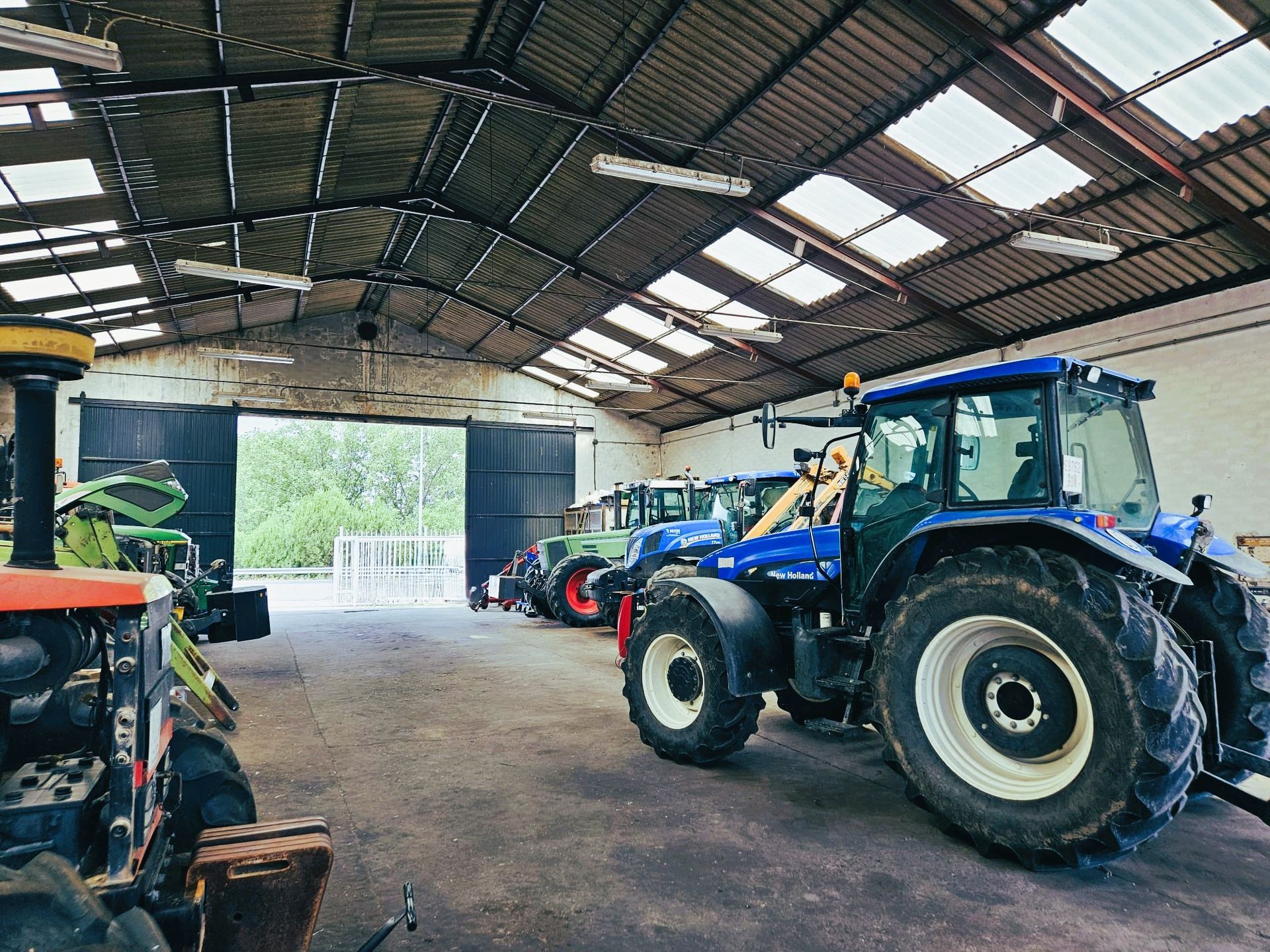 Una fila de tractores están estacionados en un almacén.