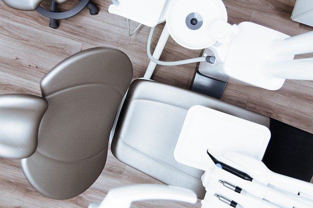 Vista superior de un sillón dental y su equipo en tonos grises y blancos.
