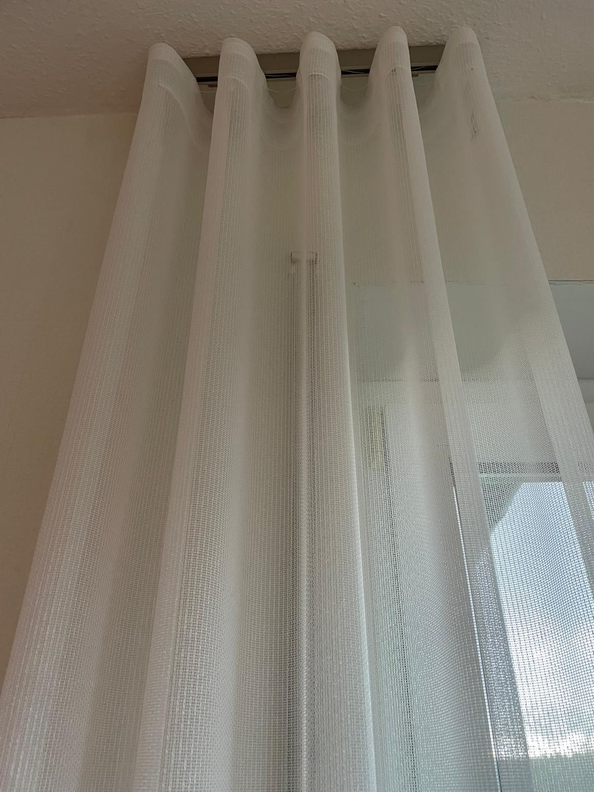 Eine Nahaufnahme eines weißen Vorhangs an einem Fenster.