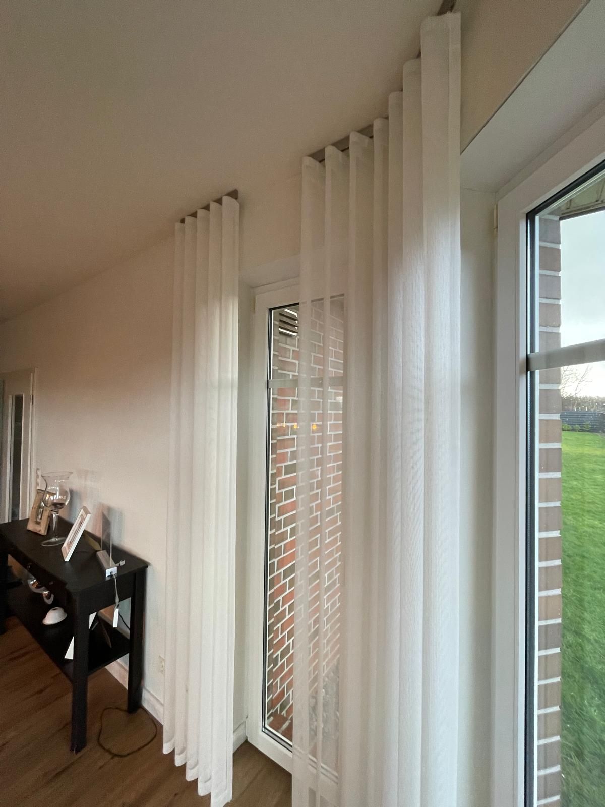 Ein Wohnzimmer mit weißen Vorhängen und einer Glasschiebetür.