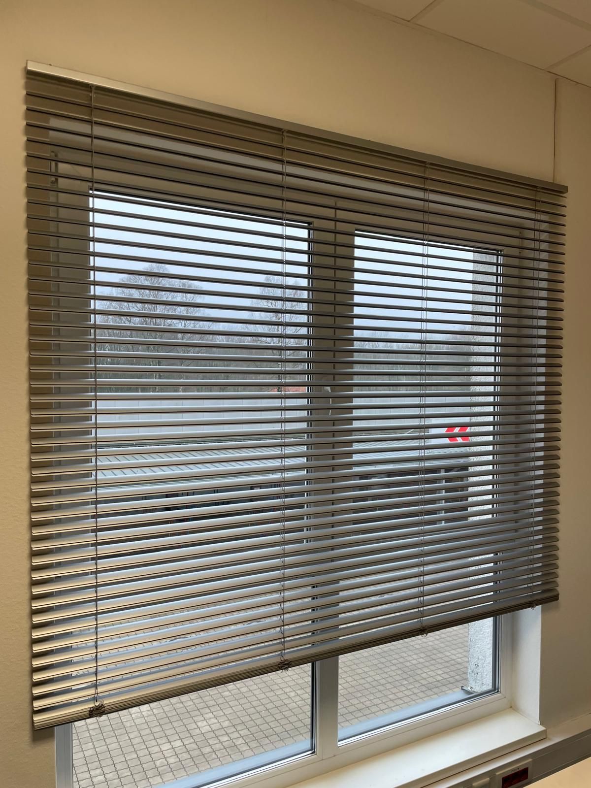 Ein Fenster mit Jalousien in einem Zimmer.