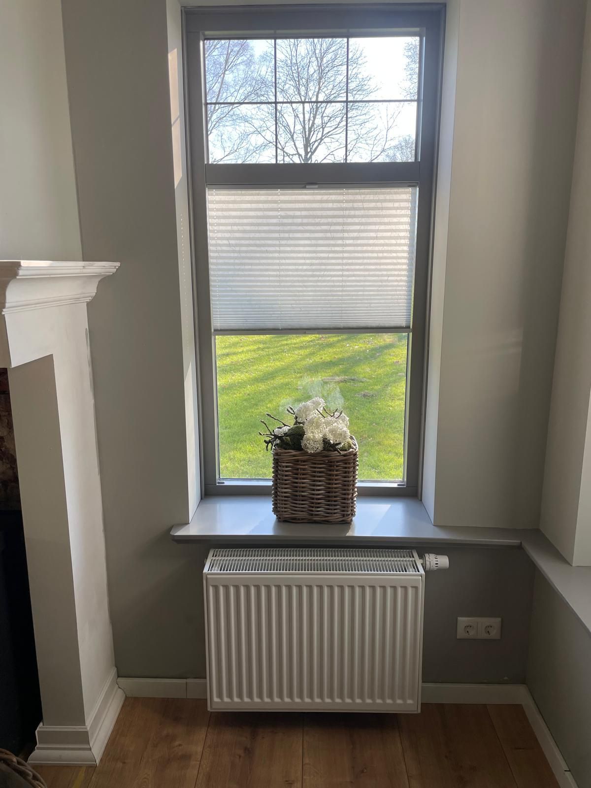 Ein Fenster mit Jalousien und einem Heizkörper in einem Wohnzimmer.