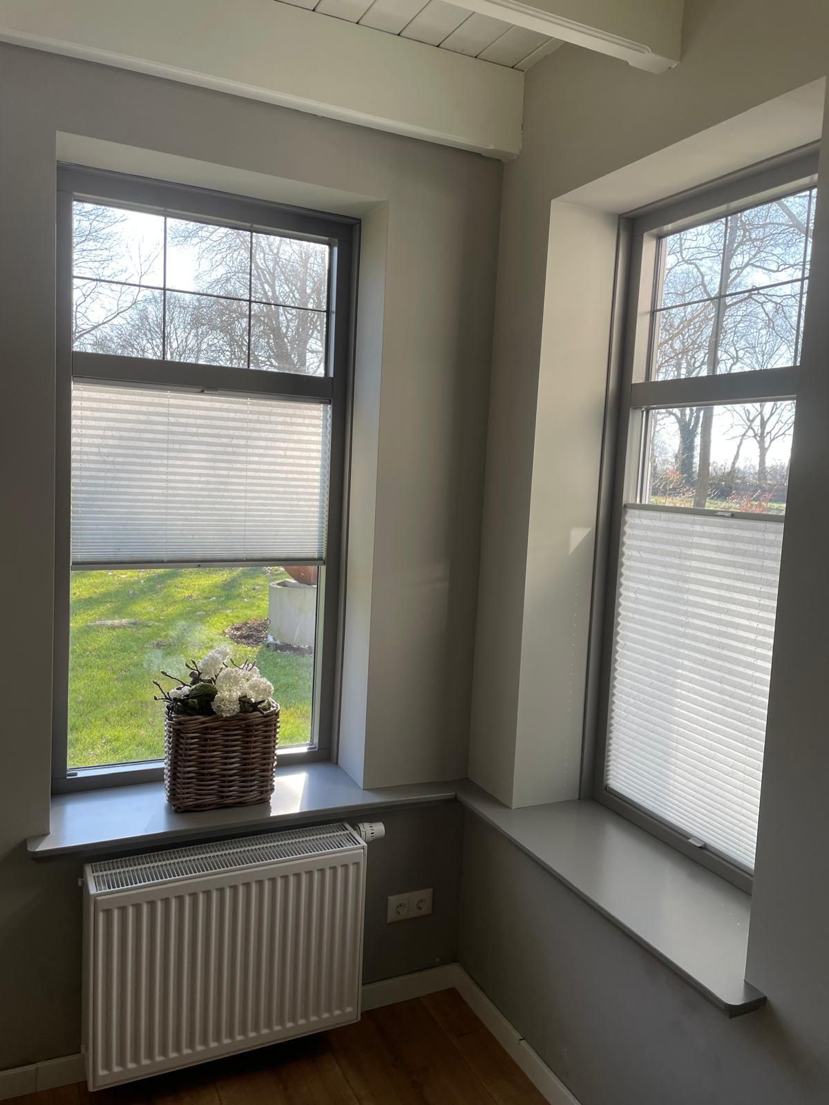 Ein Zimmer mit zwei Fenstern und einem Heizkörper auf der Fensterbank.