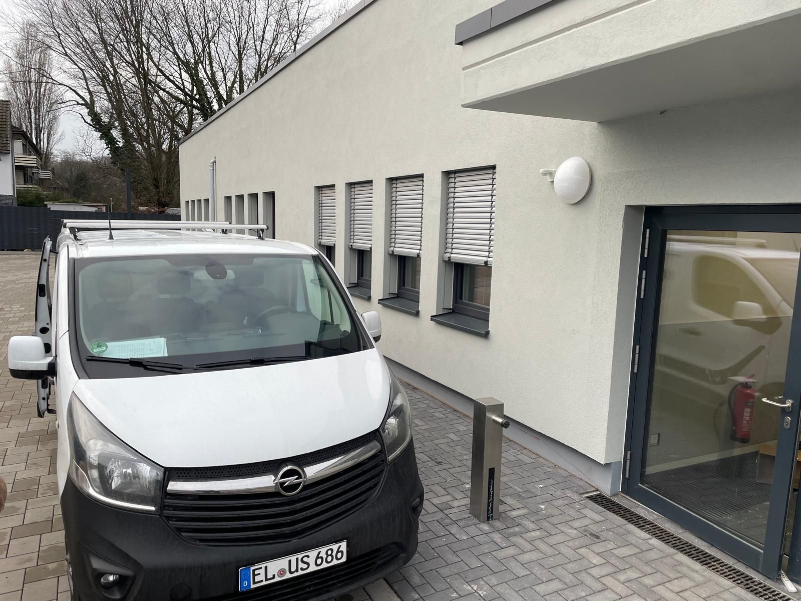 Ein weißer Lieferwagen steht vor einem Gebäude.