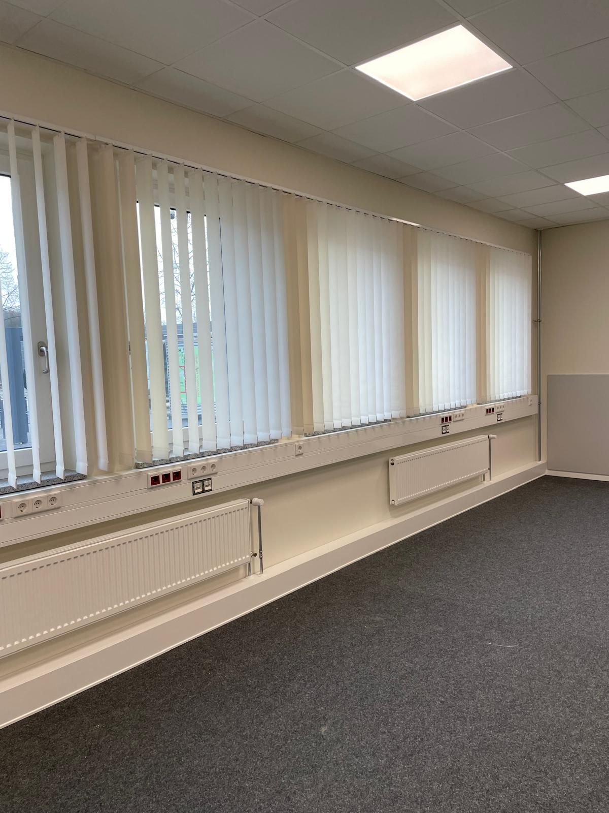 Ein leerer Raum mit vielen Fenstern und Jalousien.