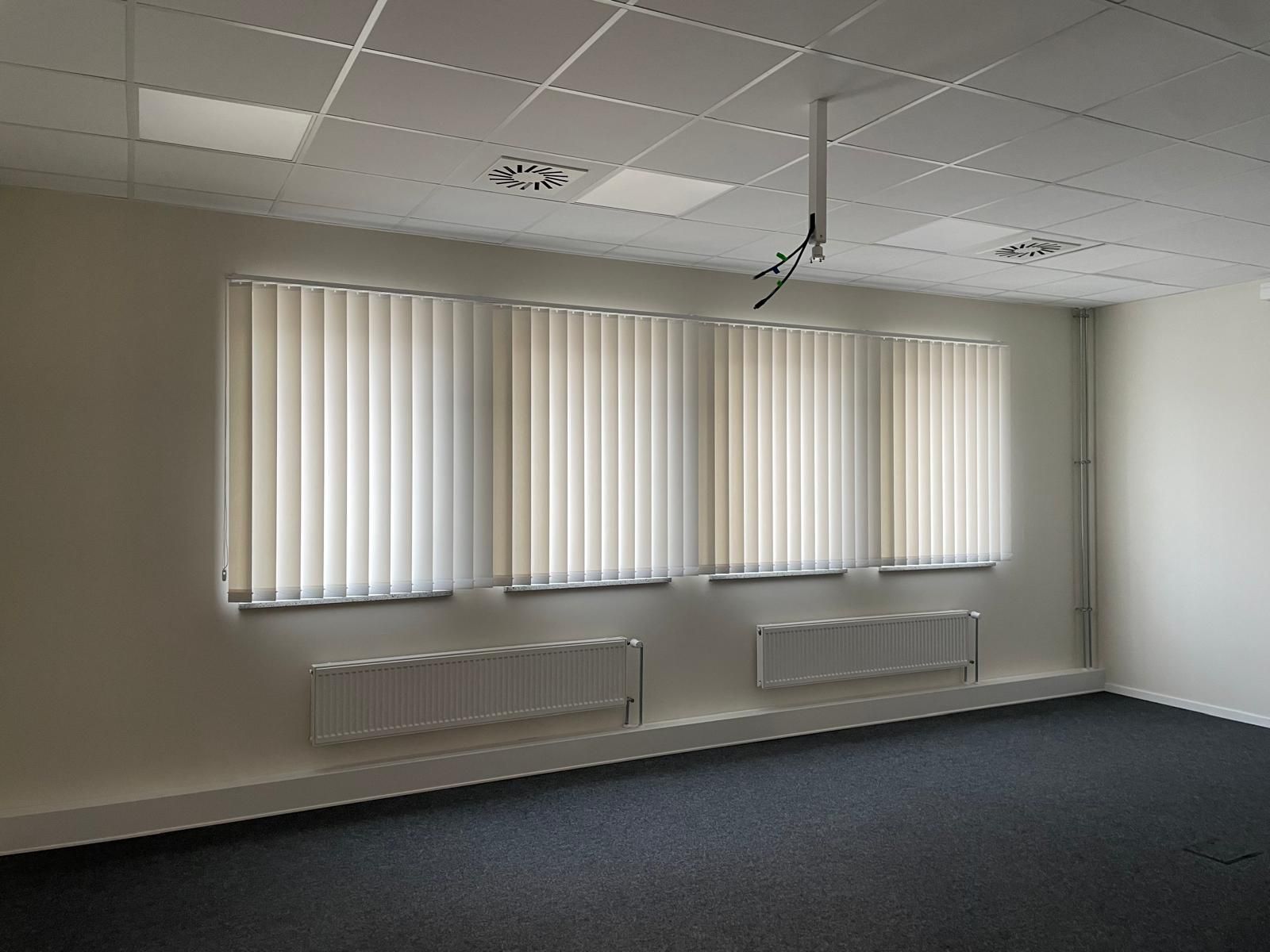 Ein Raum mit vielen Fenstern und vertikalen Jalousien