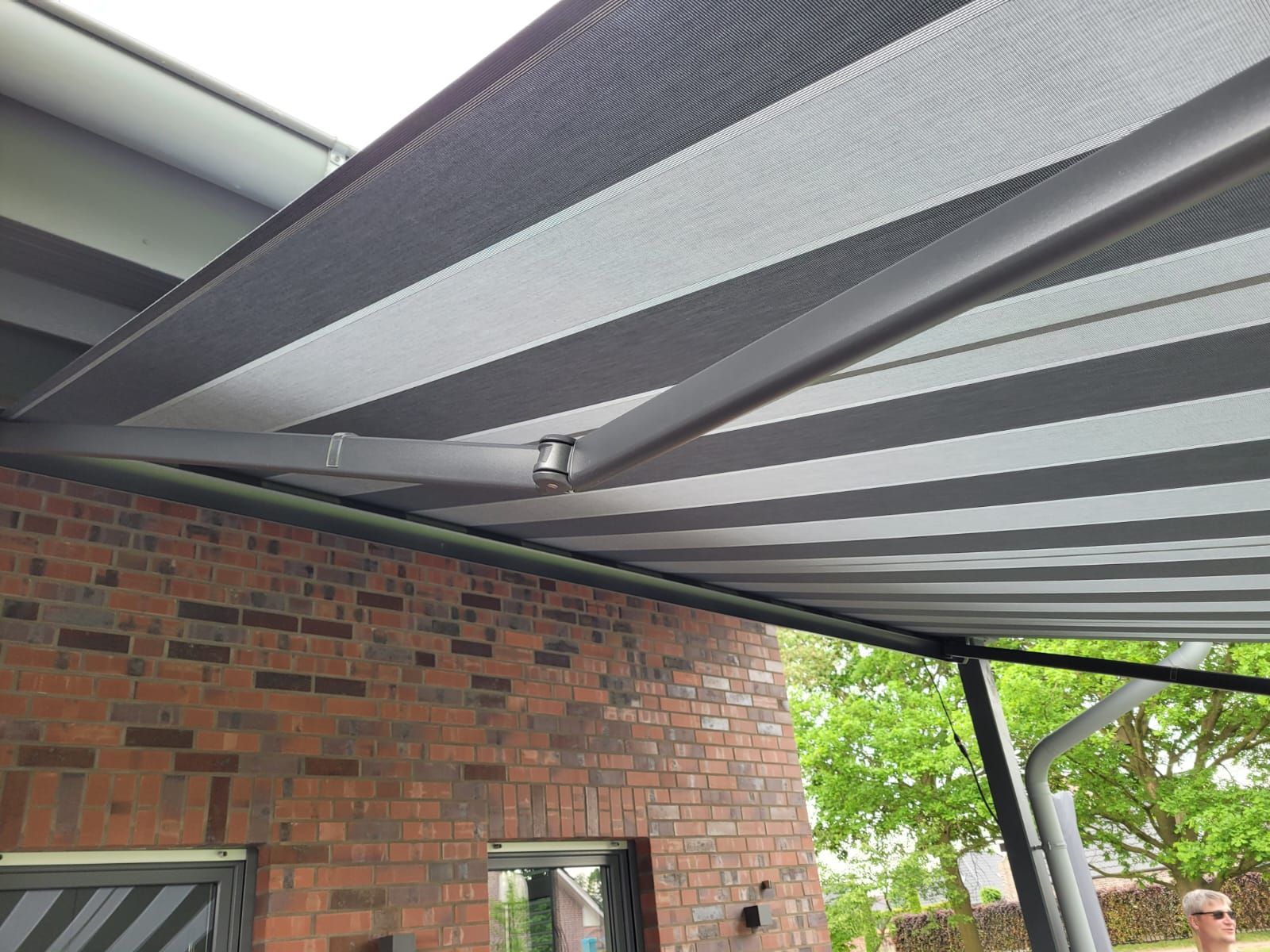 Ein Mann steht unter einer gestreiften Markise vor einem Backsteingebäude.