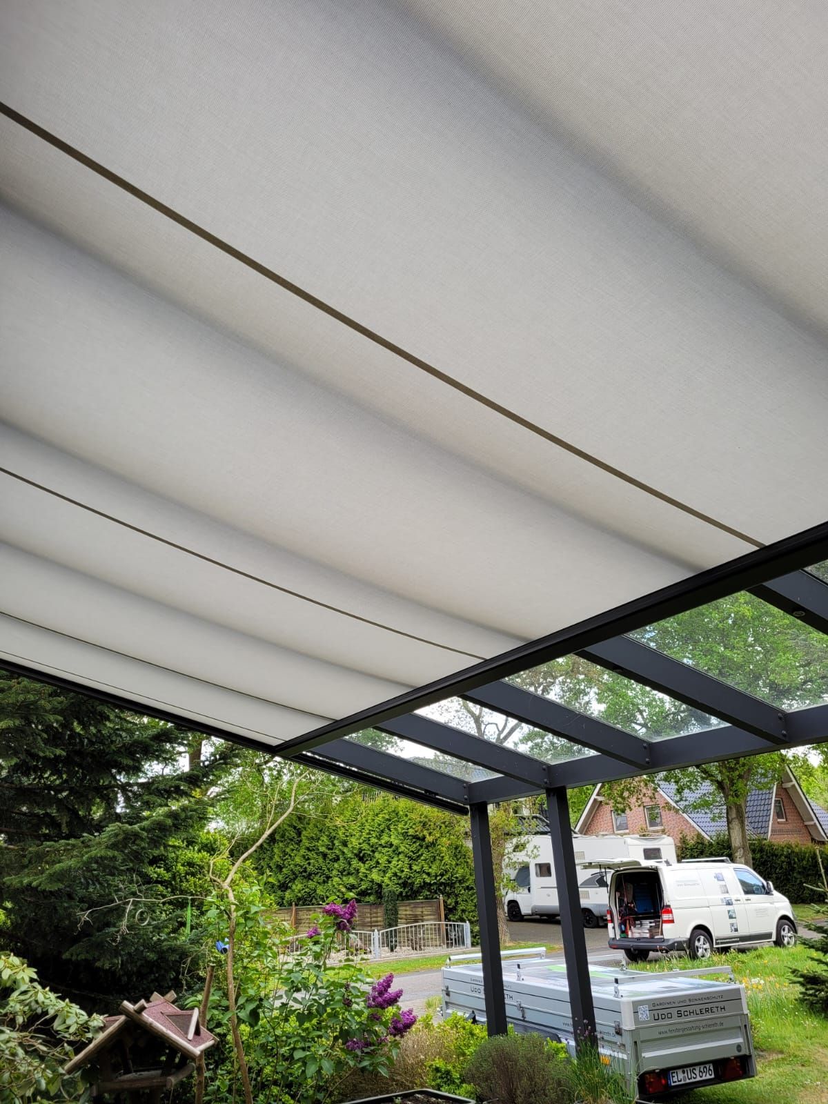 Ein Auto ist unter einem Vordach auf einer Terrasse geparkt.