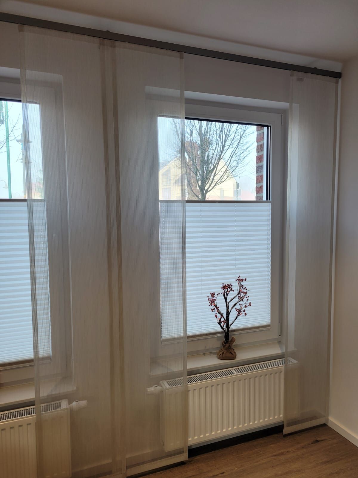 Ein Raum mit zwei Fenstern und einer Vase mit Blumen auf der Fensterbank.