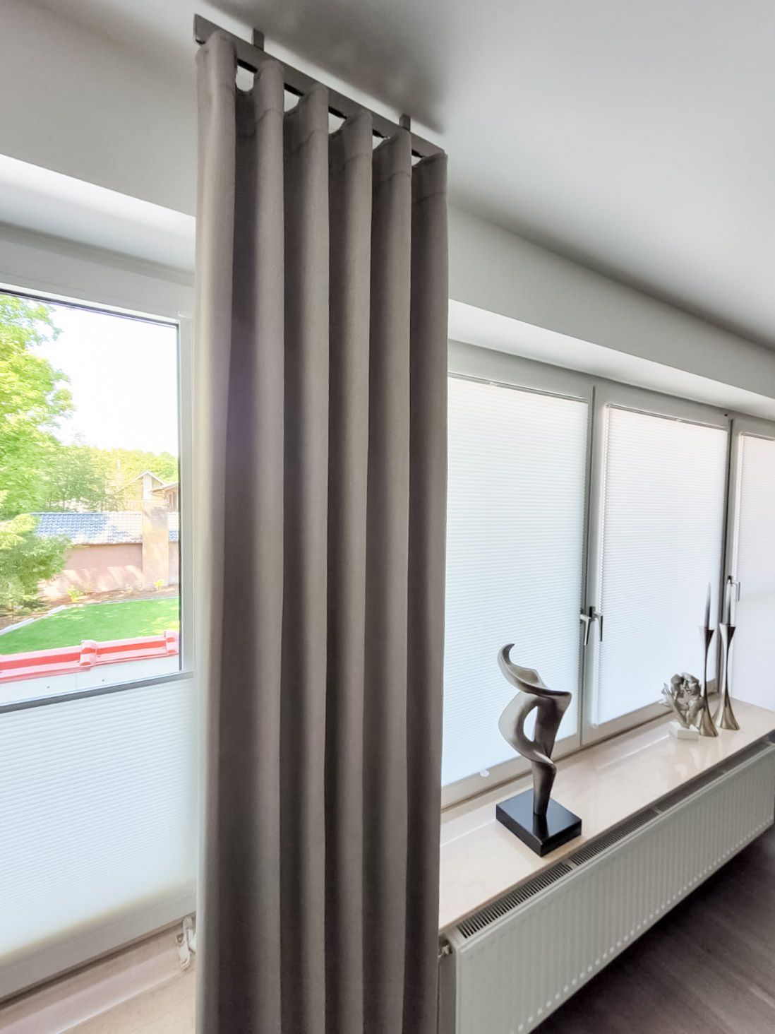 Auf dem Fensterbrett neben den Vorhängen steht eine Statue.