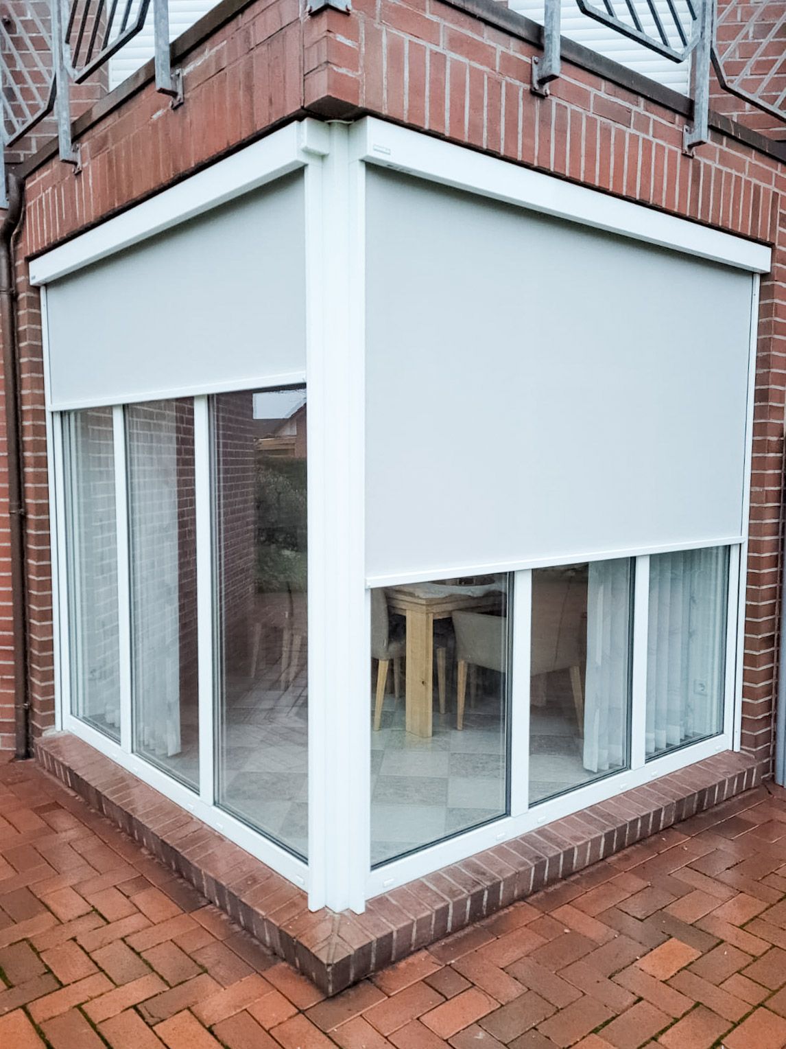 Eine Ecke eines Backsteingebäudes mit einer weißen Jalousie am Fenster.