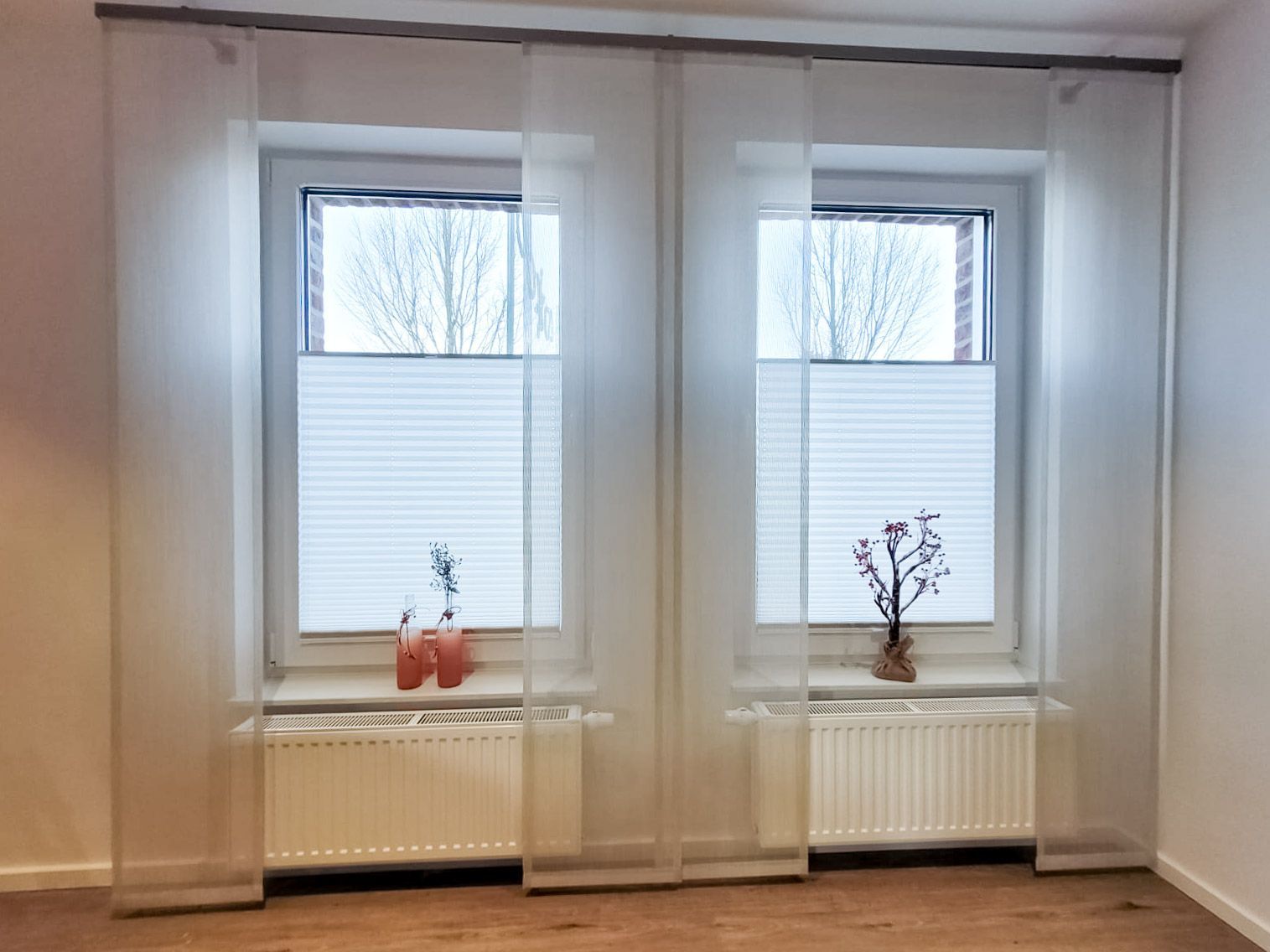 Ein Raum mit zwei Fenstern und einer Vase auf der Fensterbank