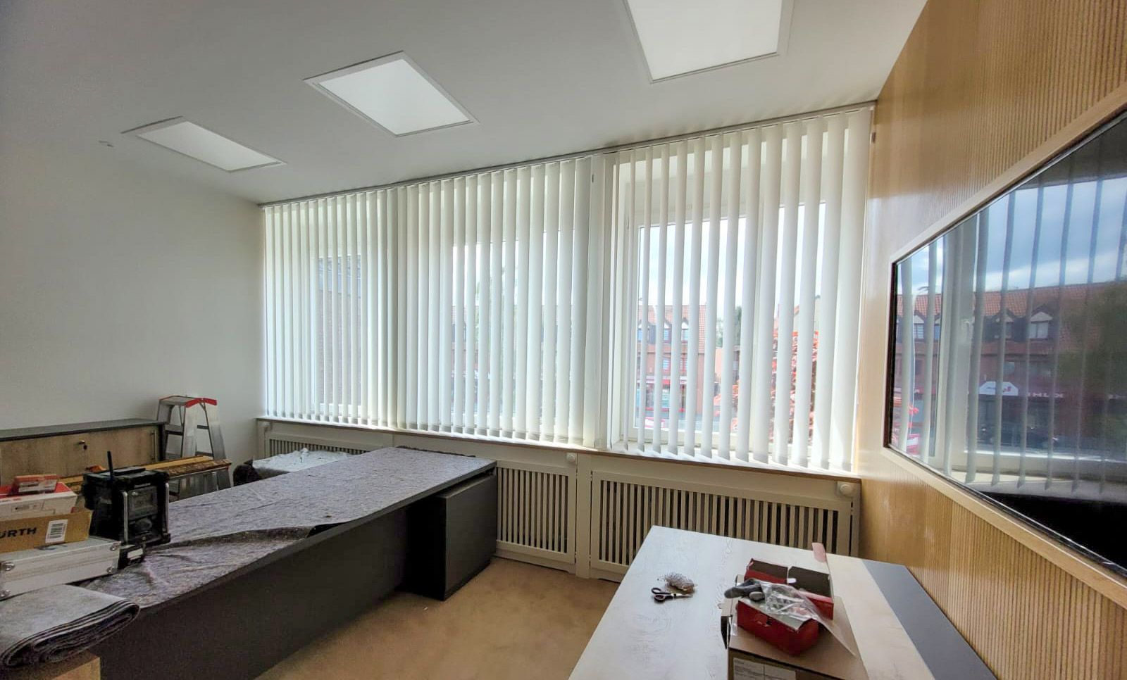 Ein Raum mit vielen Fenstern und Vertikaljalousien.