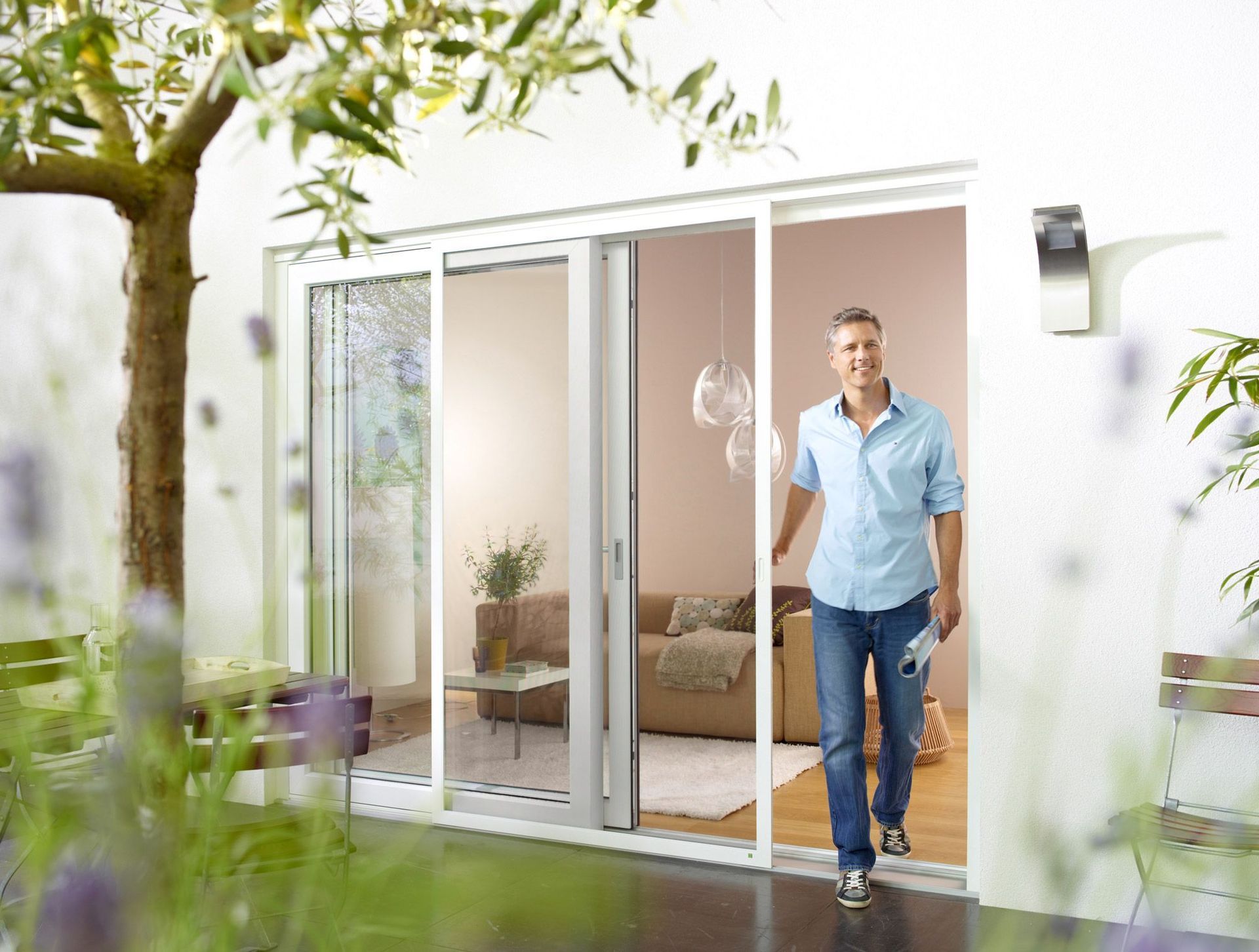 Ein Mann verlässt ein Wohnzimmer durch eine Glasschiebetür.