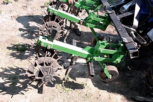 Una máquina verde y negra está sentada en el suelo al lado de un tractor.