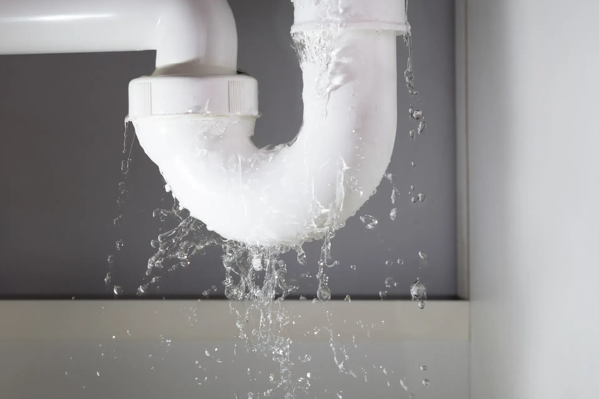 Una tubería del fregadero tiene una fuga de agua y sale agua de ella.