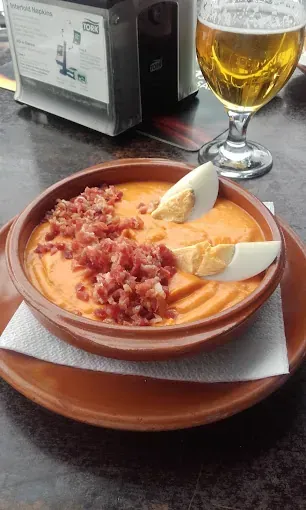 Un plato de comida con huevos y tocino en un plato junto a un vaso de cerveza.