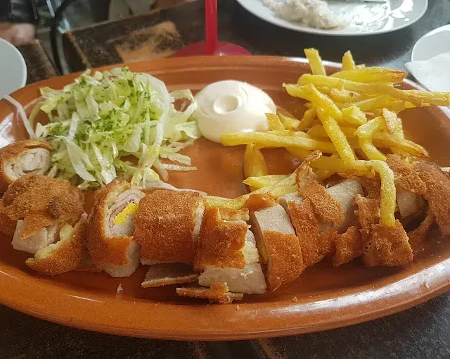 Un plato de comida con patatas fritas y lechuga sobre una mesa.