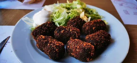 Un plato de comida con falafel y una ensalada en una mesa.