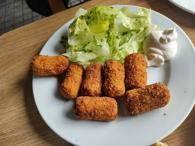 Un plato blanco cubierto con comida frita y una ensalada.