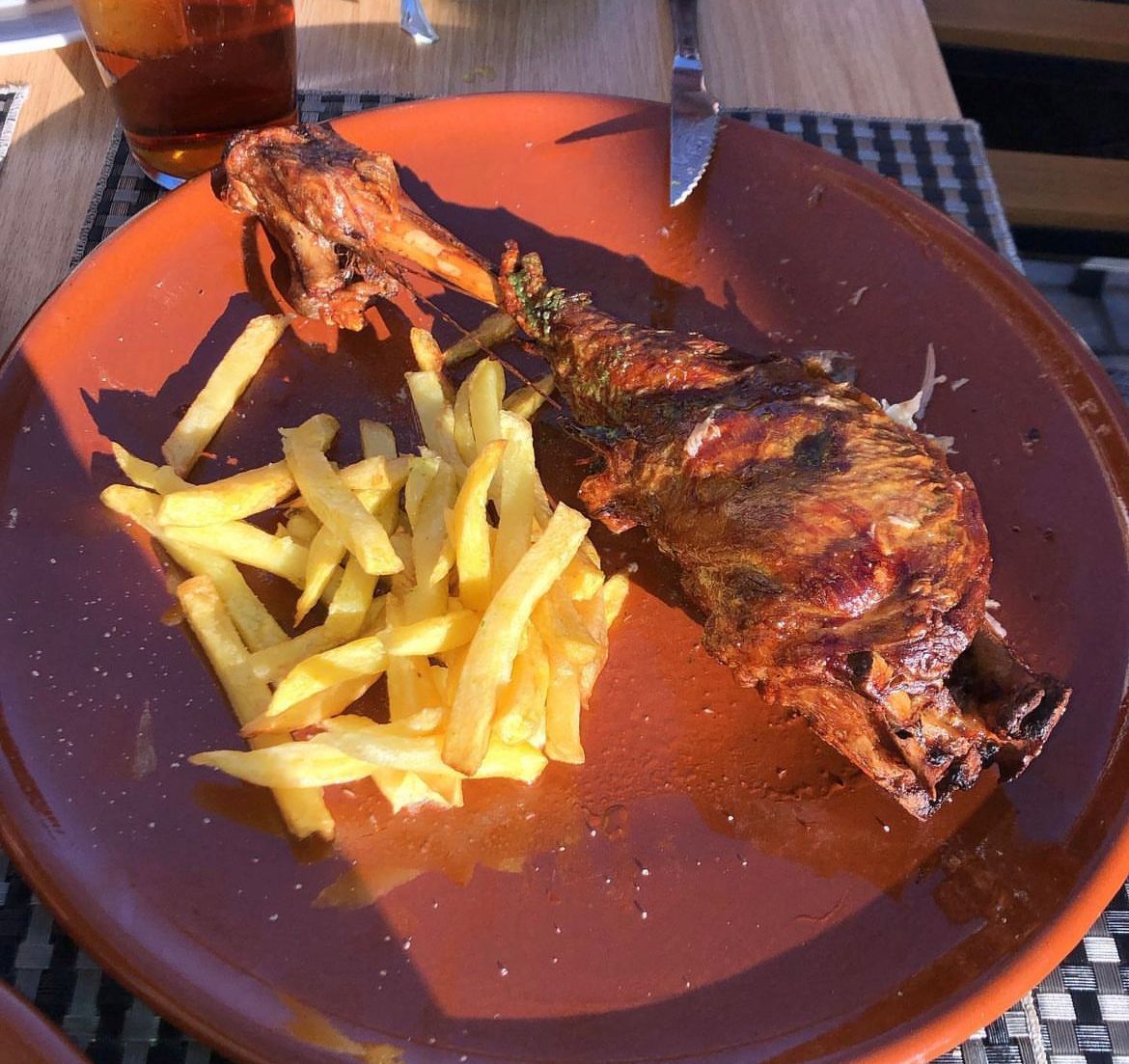 Un plato de comida con carne y papas fritas encima.