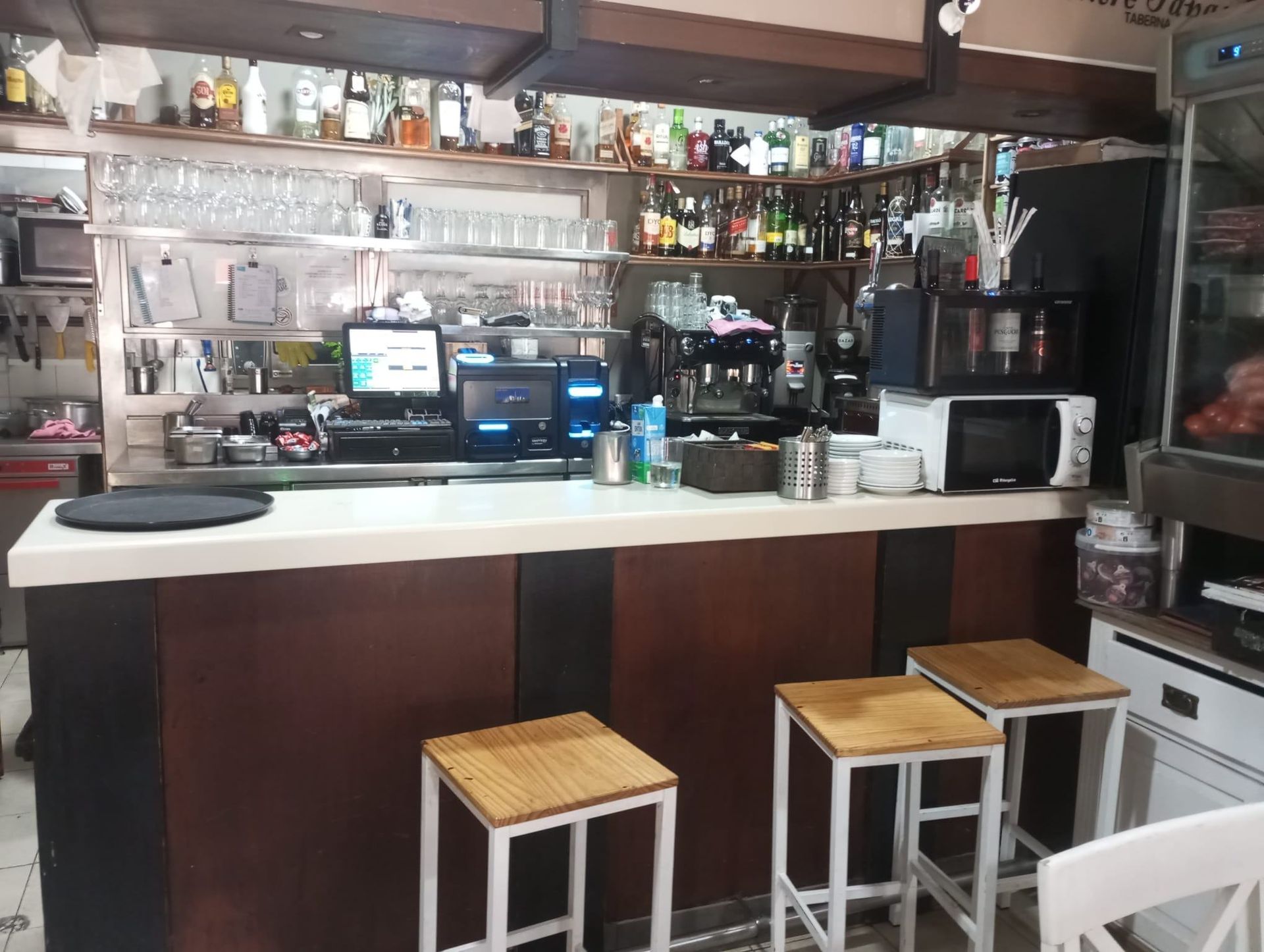 Un bar con taburetes y botellas en los estantes.