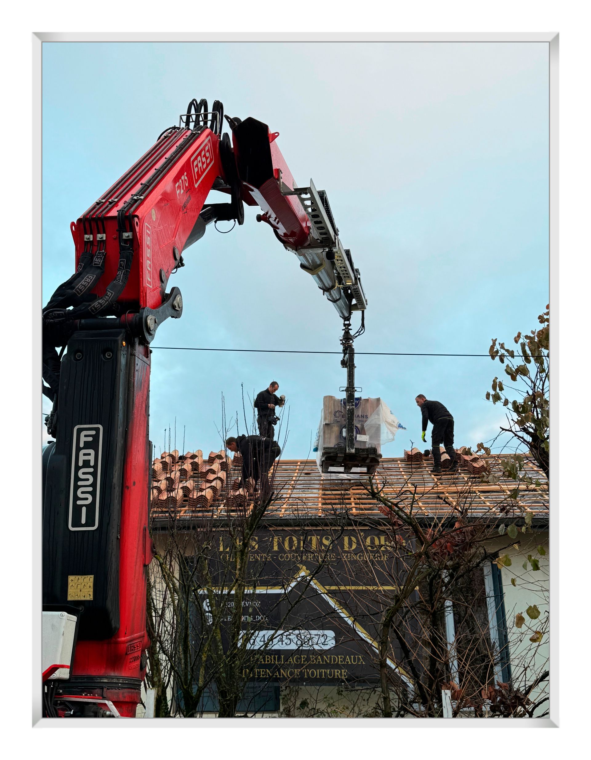 Toit de tuiles rouges sur un bâtiment aux murs en stuc patiné. Ciel nuageux au-dessus.