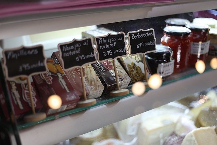 Frascos y etiquetas variadas en una vitrina de delicatessen, con velas encendidas y dulces envasados ​​en los estantes.