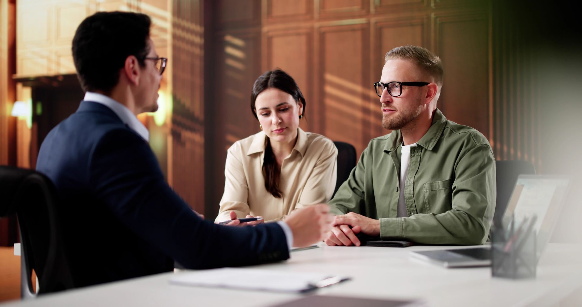 Une personne en costume rencontre deux autres personnes autour d'un bureau dans un environnement de bureau professionnel.