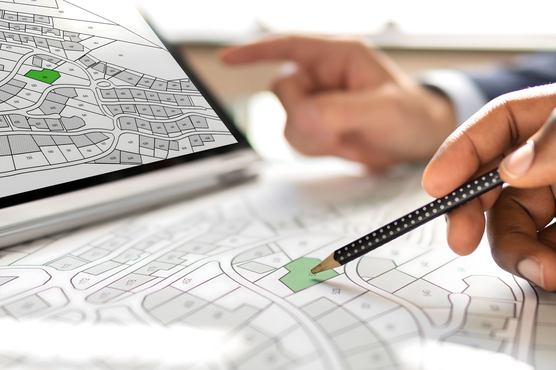 Une personne utilise un crayon pour analyser une carte, en parallèle avec une carte numérique sur un ordinateur portable.