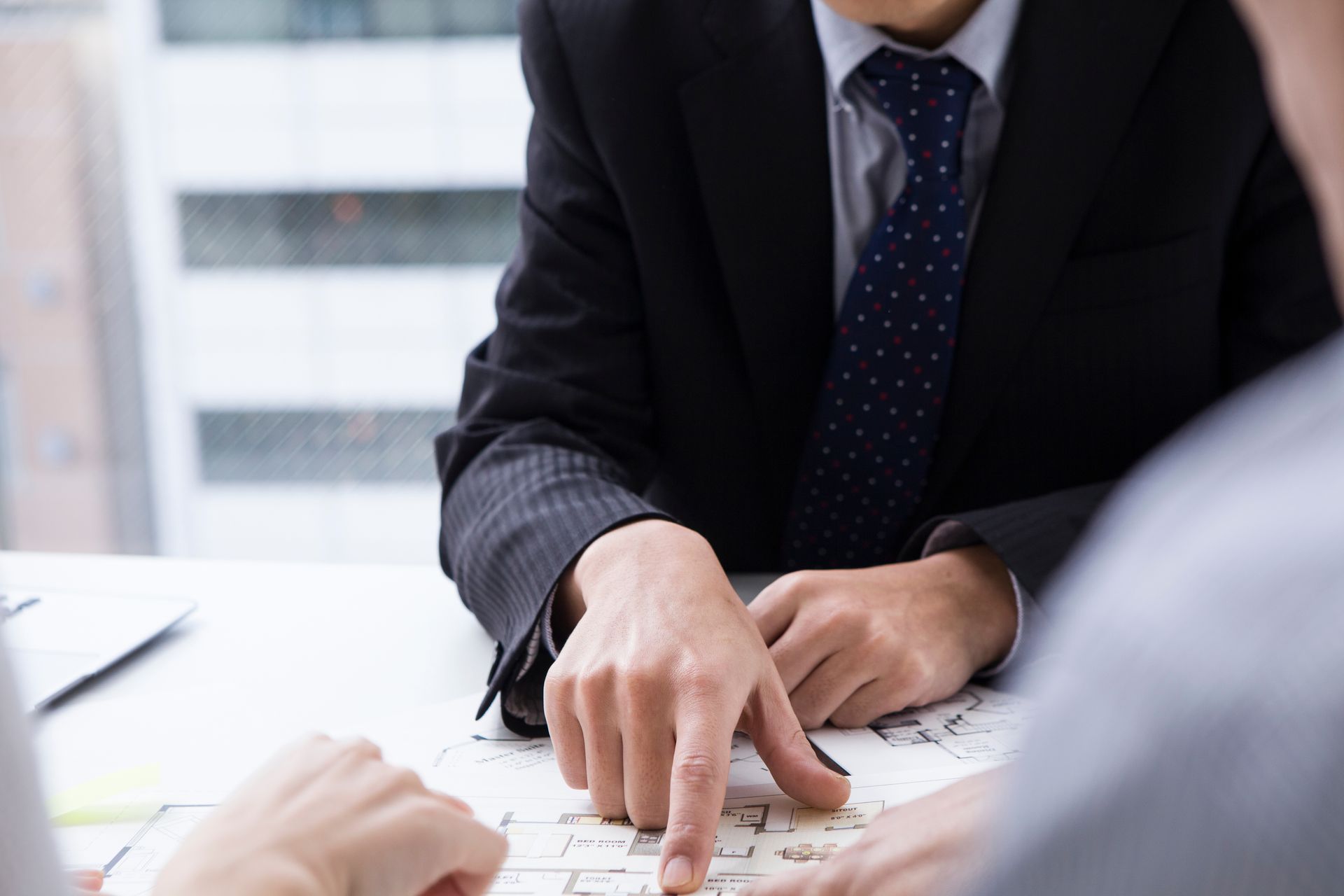 Un homme d'affaires désigne un document posé sur une table lors d'une réunion.