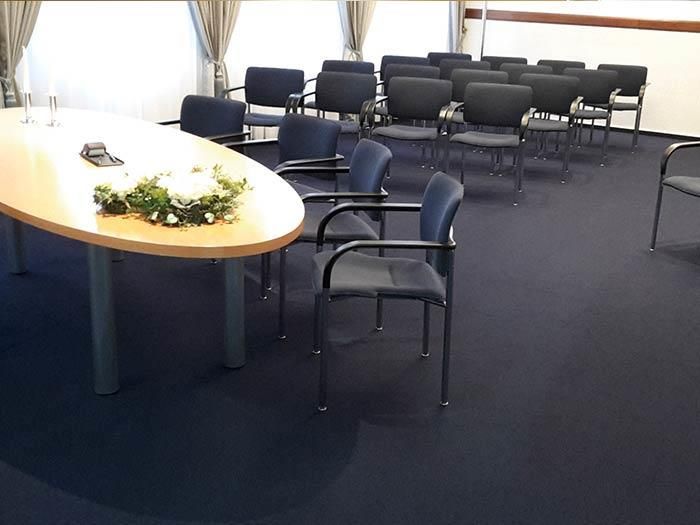 Ein Raum mit Stuhlreihen und einem Tisch mit Blumen darauf