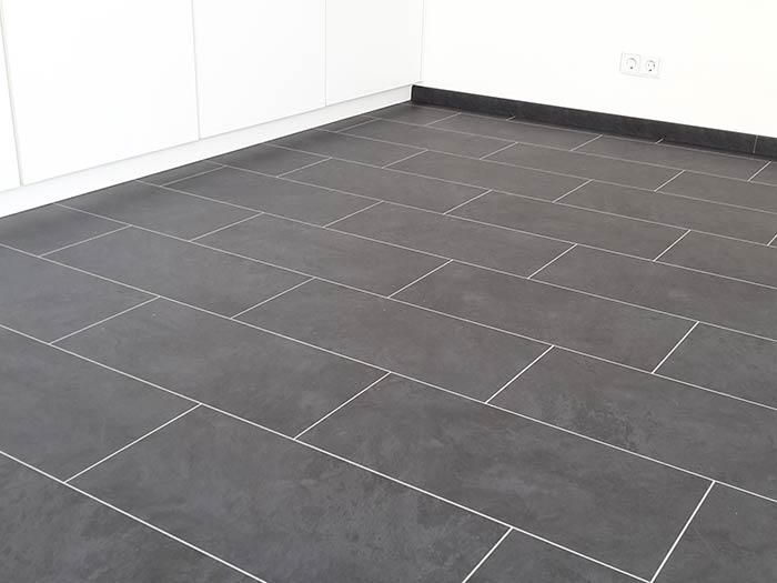 Eine Küche mit schwarzem Fliesenboden und weißen Schränken.