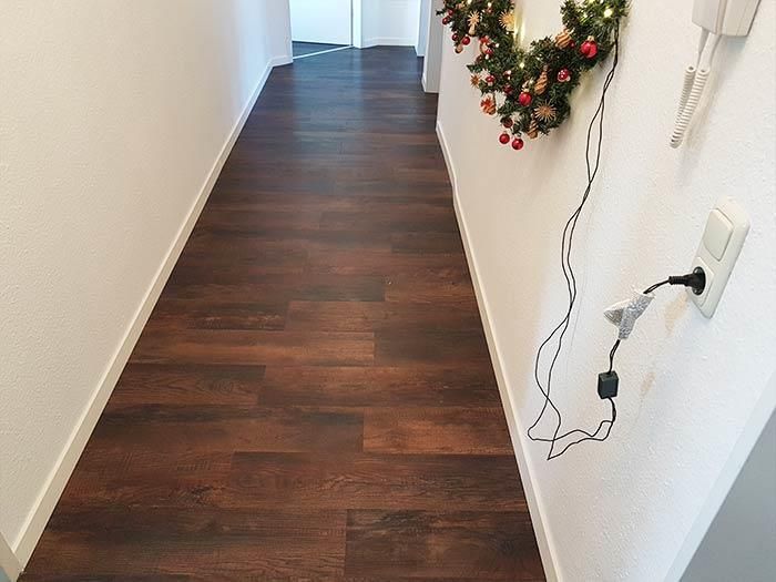 Ein Flur mit Holzboden und einem Weihnachtskranz an der Wand.