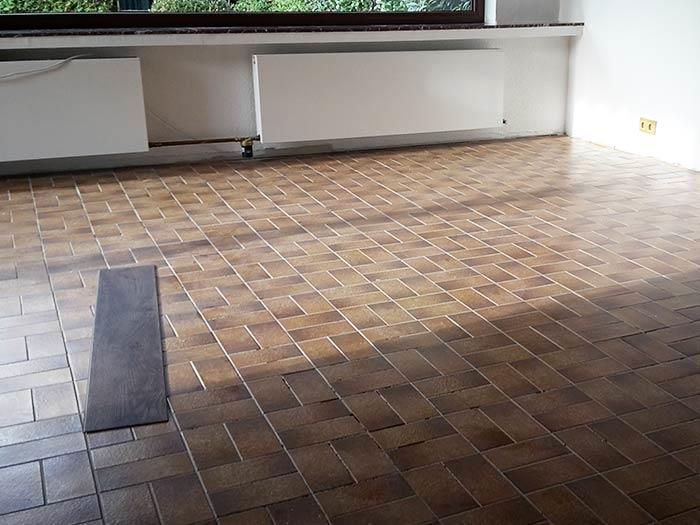 Ein leerer Raum mit gefliestem Boden und einem Fenster