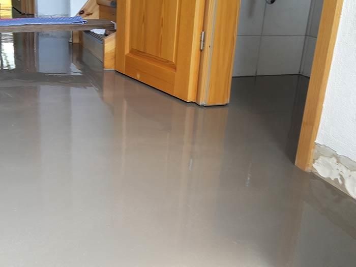 In einem Raum mit glänzendem Boden steht eine Tür offen.