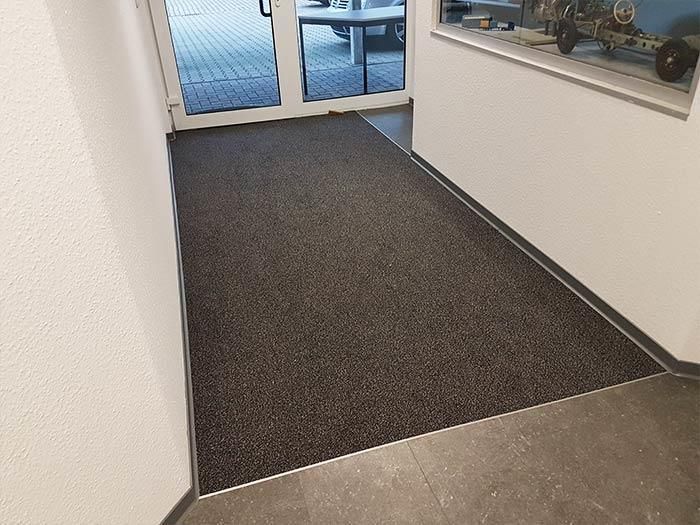 Ein Flur mit einer Tür und einem Teppich auf dem Boden.