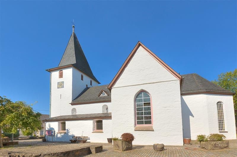 Eine weiße Kirche mit einem Kirchturm und einem blauen Himmel im Hintergrund