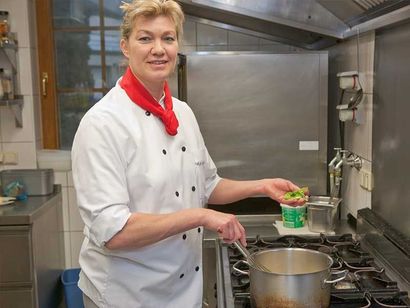Eine Frau in Kochuniform bereitet in einer Küche Essen zu