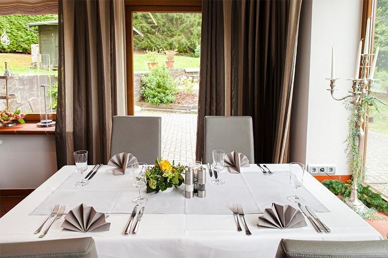 Ein Esstisch mit weißer Tischdecke und Besteck