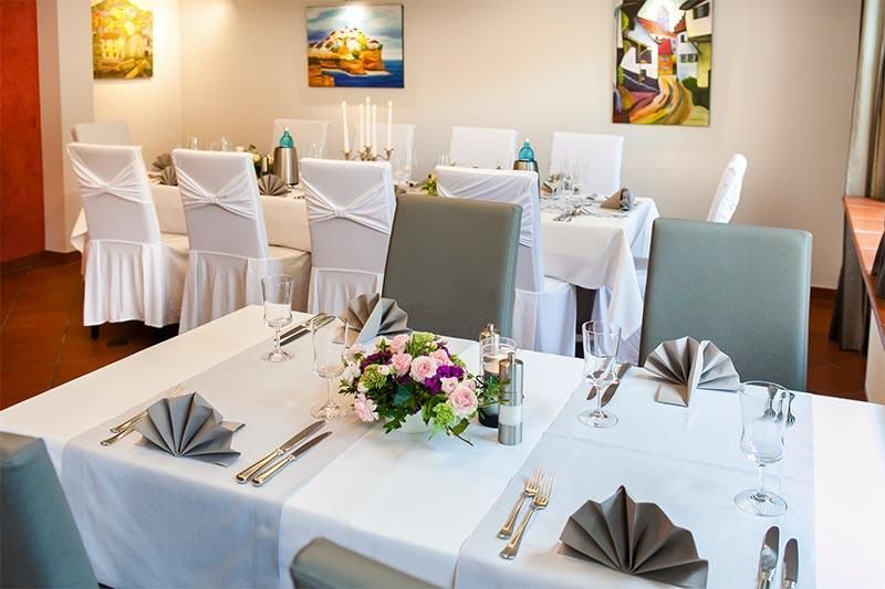 Ein Esszimmer mit Tischen und Stühlen und Blumen auf dem Tisch