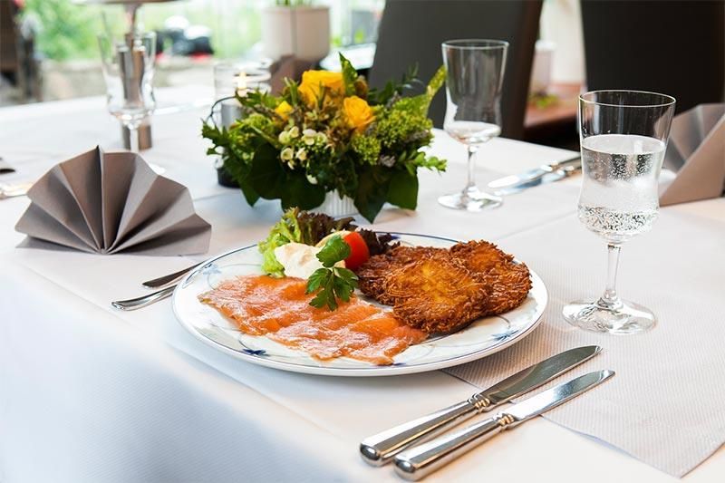 Ein Teller mit Essen auf einem Tisch mit einer Vase mit Blumen im Hintergrund