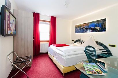 Ein Hotelzimmer mit einem großen Bett und einem Flachbildfernseher