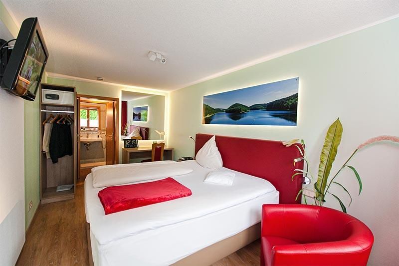 Ein Hotelzimmer mit zwei Betten und einem roten Stuhl