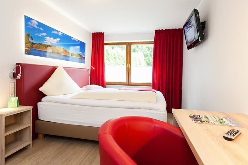 Ein Hotelzimmer mit einem Bett und einem roten Stuhl