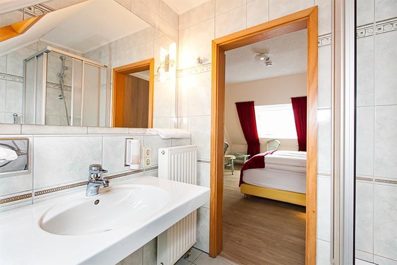 Ein Badezimmer mit Waschbecken und Spiegel, das zu einem Schlafzimmer führt